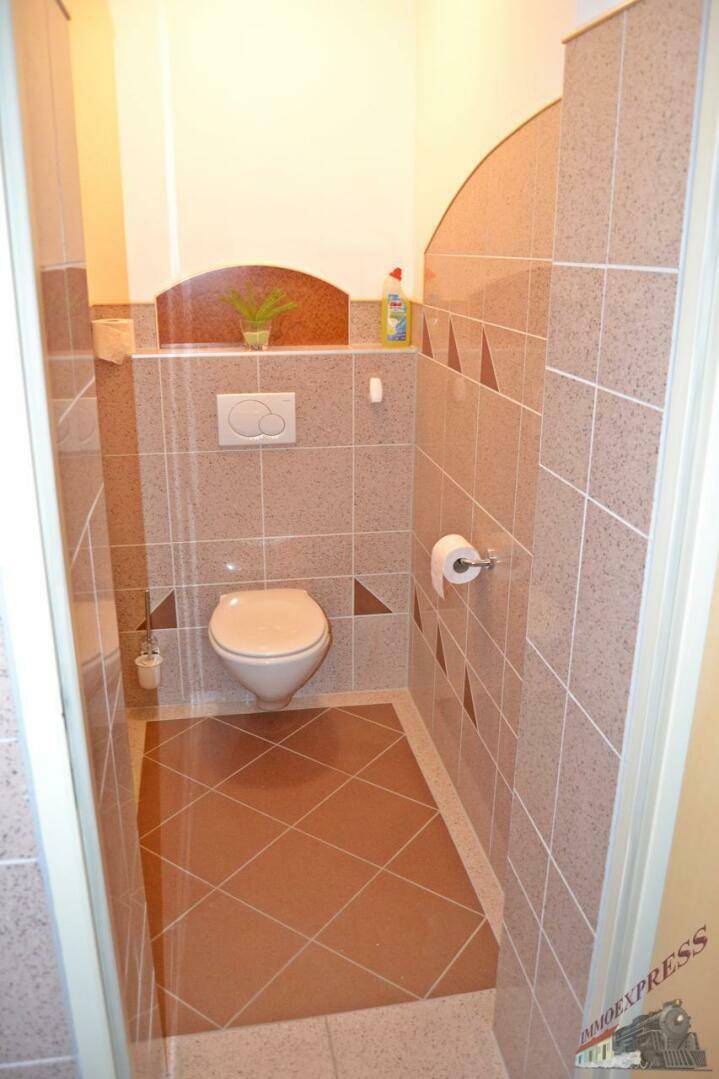 Kleines Gäste-WC mit modernen Fliesen in Erdtönen und wandhängendem WC, sauber und funktional.