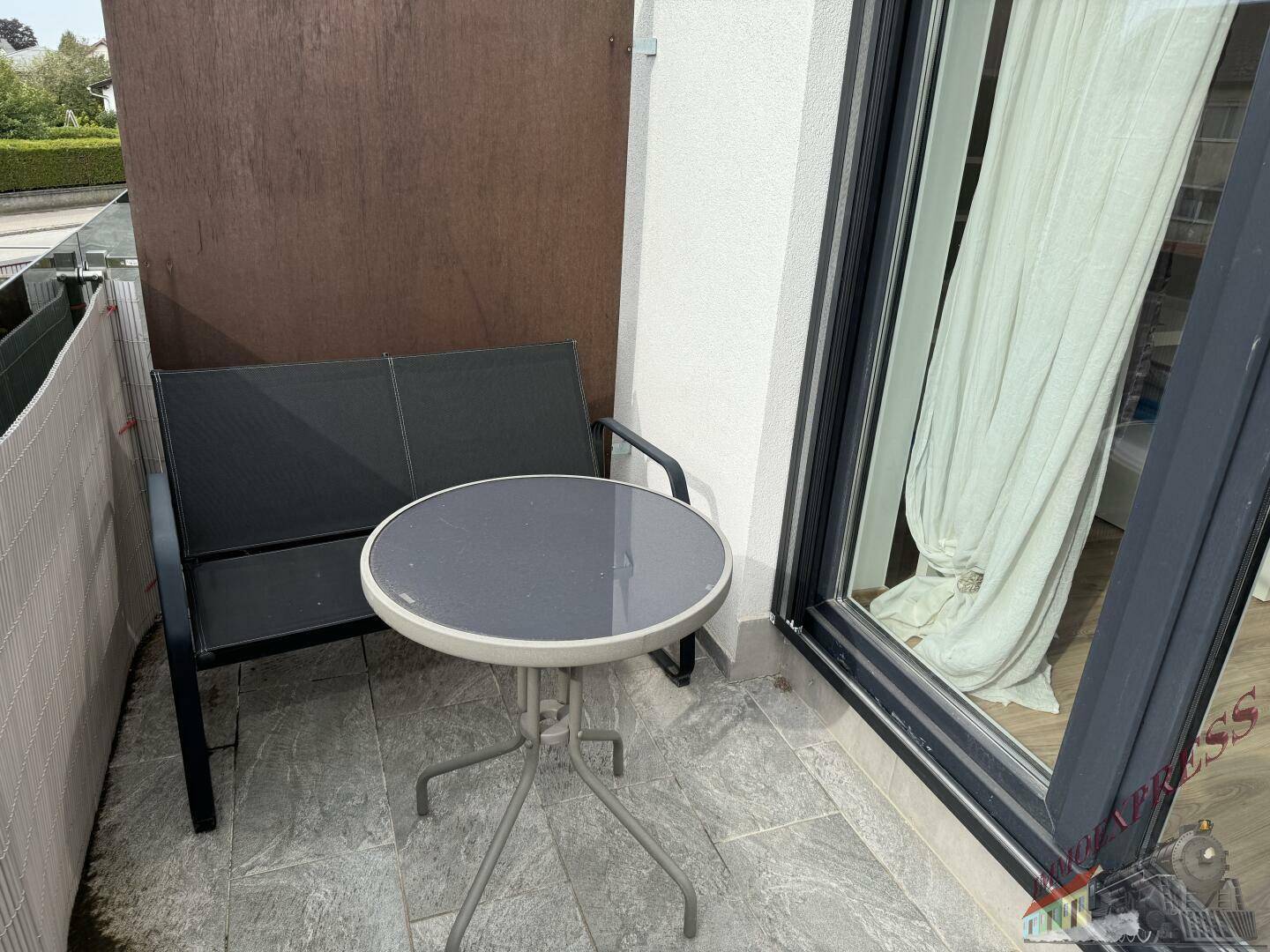 Kleiner Balkon mit Tisch und Bank, perfekt für eine Kaffeepause im Freien.