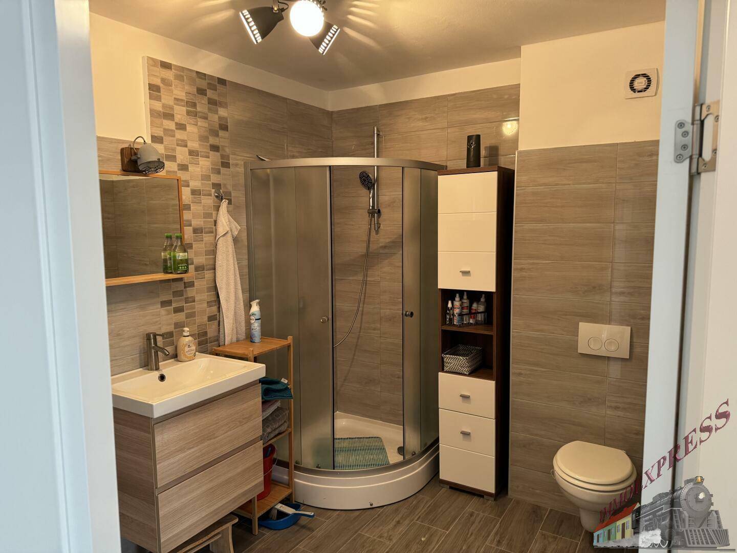 Modernes Badezimmer mit Eckdusche, Waschtisch und Wand-WC in hellen Fliesen.