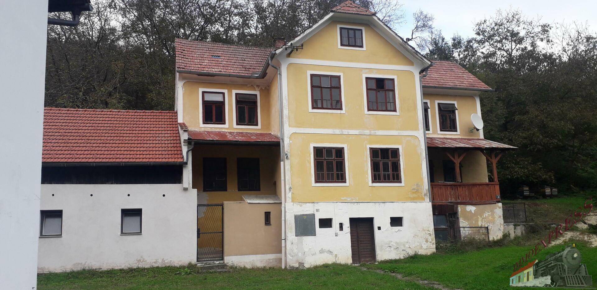 Gesamtansicht des gelben Hauses mit mehreren Fenstern und einem kleinen Holzbalkon.