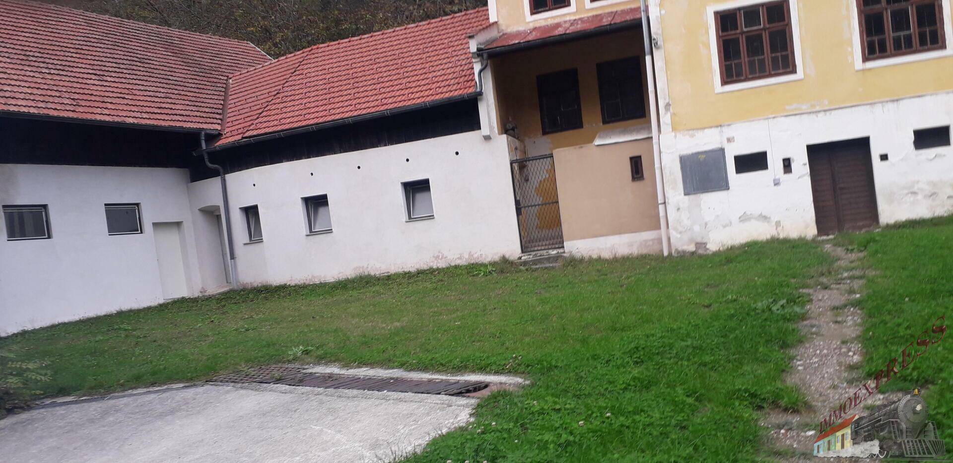 Seitenansicht der Gebäude mit einer leicht abfallenden Rasenfläche und Zufahrt.