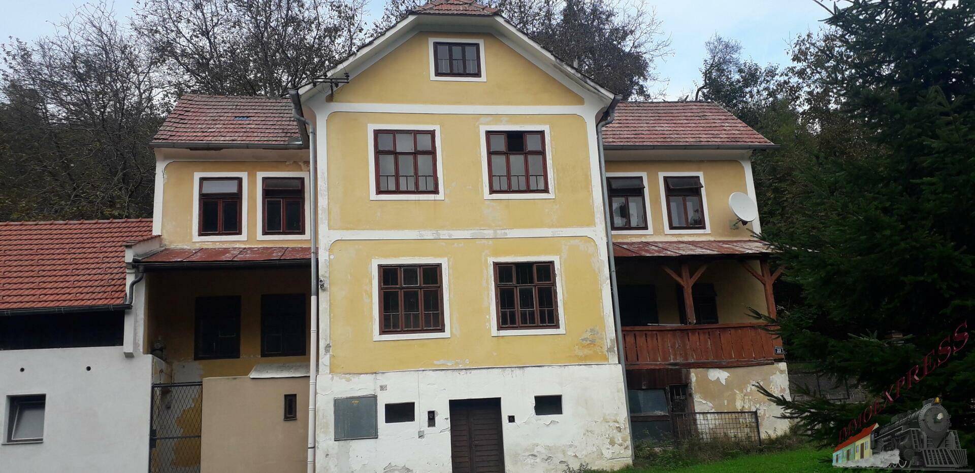 Vorderansicht des gelben Hauptgebäudes mit traditioneller Architektur und Holzbalkon.