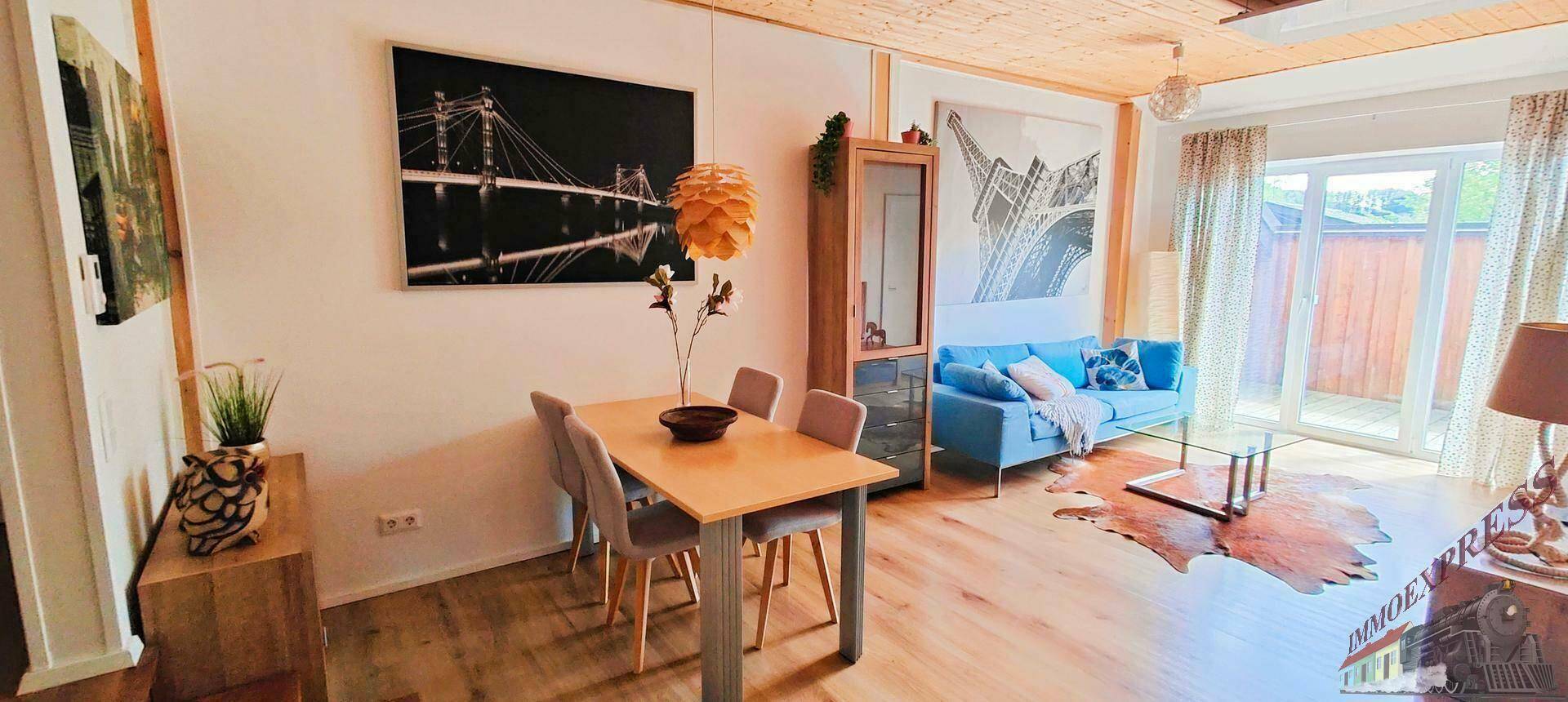 Heller Wohn-Essbereich mit Holzboden, Essgruppe und Zugang zu einem Außenbereich durch eine Terrassentür.