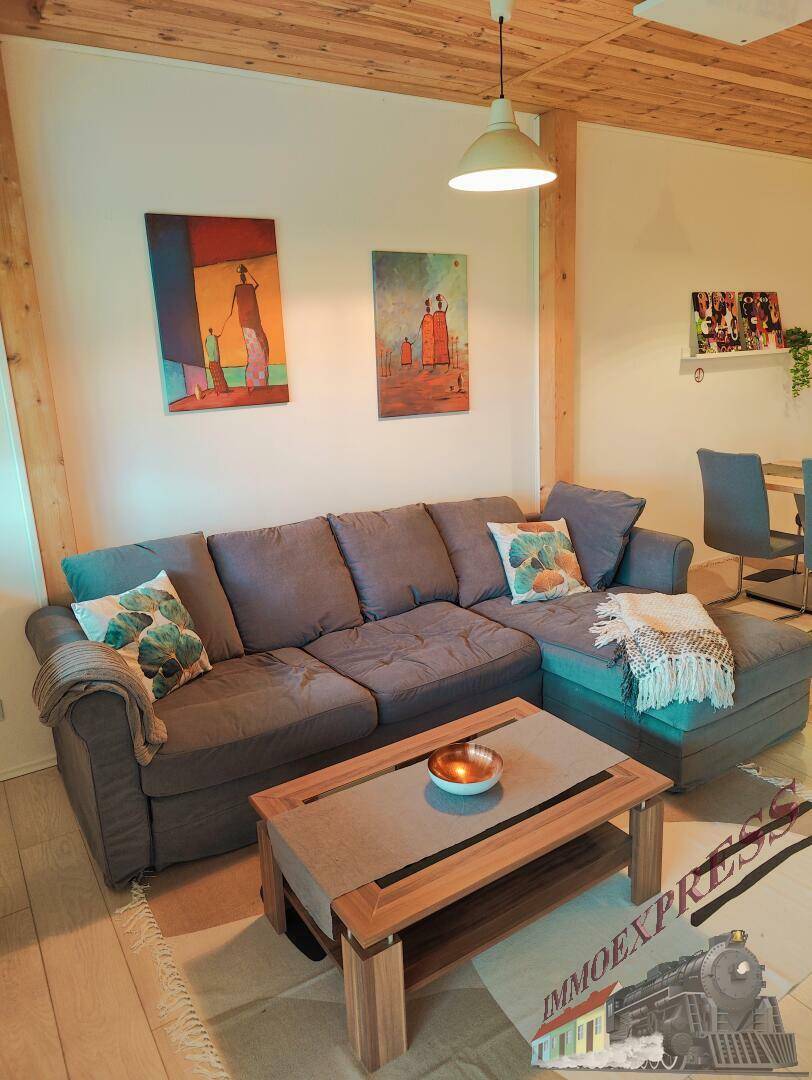 Komfortables Wohnzimmer mit großem Ecksofa, Couchtisch und farbenfrohen Kunstwerken an der Wand, einladend gestaltet.