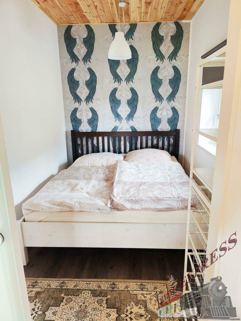 Schlafzimmer mit Holzboden, dekorativer Tapete und einem gemütlichen Doppelbett, modern und einladend gestaltet.