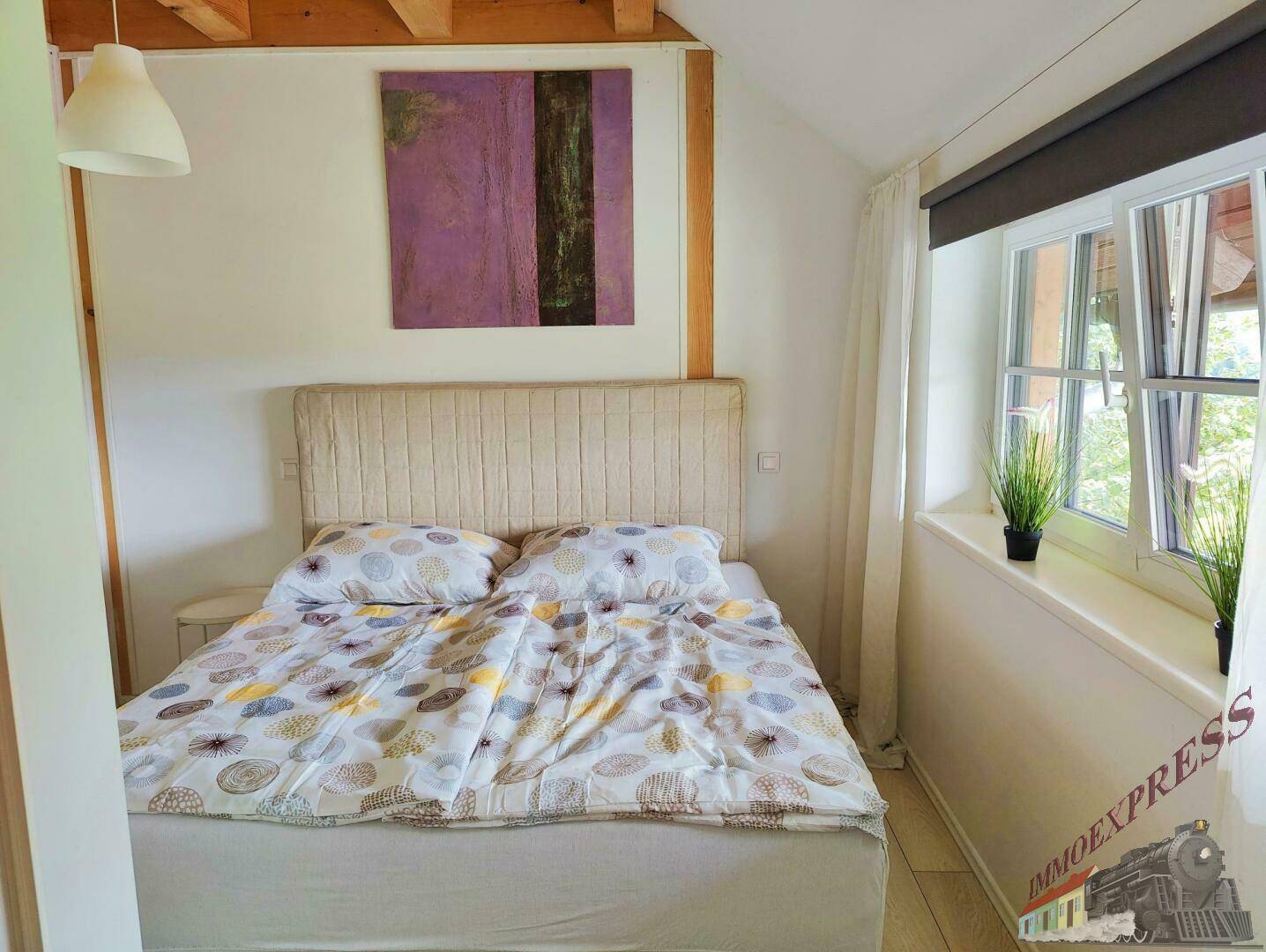 Helles Schlafzimmer mit Doppelbett, Holzbalken und Fenster mit Blick ins Grüne, bietet eine ruhige Atmosphäre.