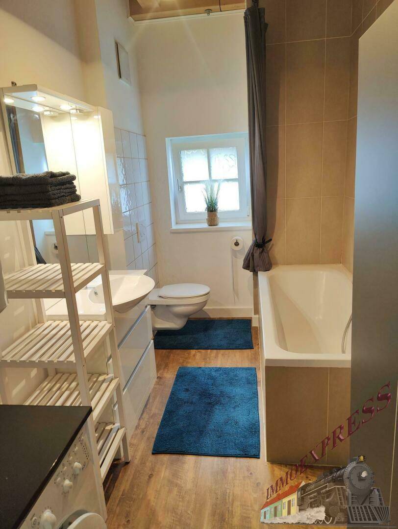 Funktionales Badezimmer mit Badewanne, WC, Waschmaschine und Fenster für Tageslicht, praktisch eingerichtet.