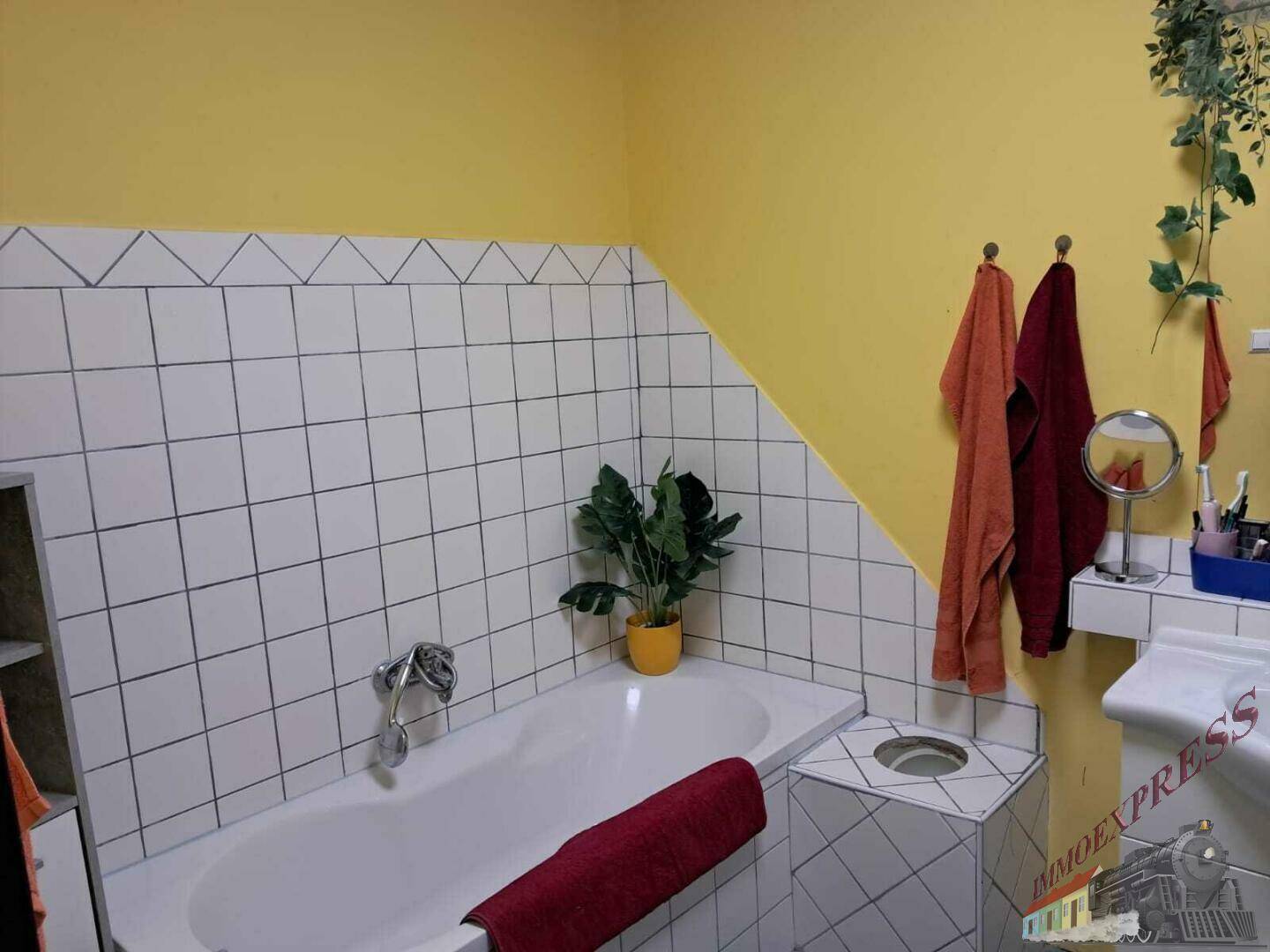 Das Badezimmer verfügt über eine Badewanne, gelbe Wände und weiße Fliesen mit Dachschräge.