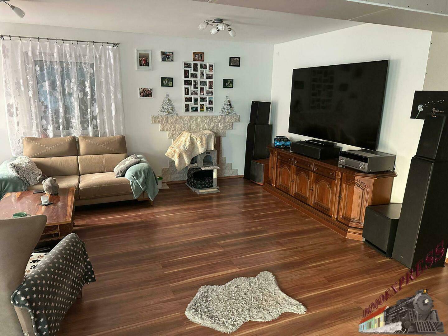Helles Wohnzimmer mit Holzboden, bequemen Sofas und einem großen Fernseher.
