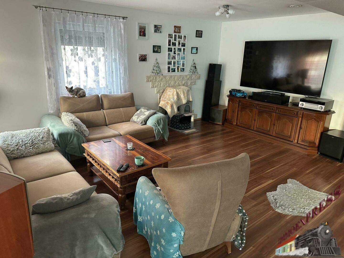 Geräumiges Wohnzimmer mit Holzboden, bequemen Sofas und einem großen Fernseher.