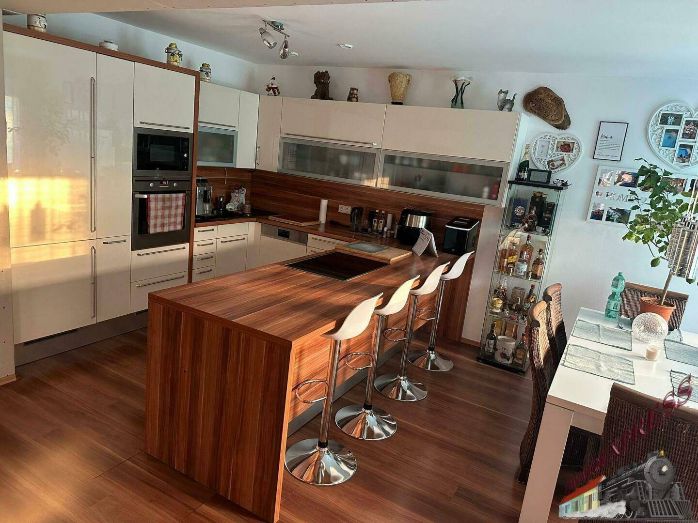 Moderne Einbauküche mit glänzenden weißen Fronten, Holzinsel und integrierten Geräten.