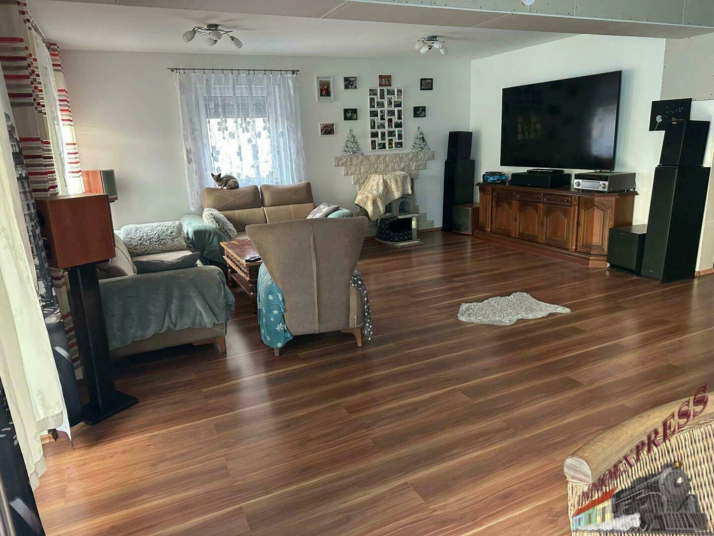 Gemütliches Wohnzimmer mit Holzboden, bequemen Sofas und einem großen Fernseher.