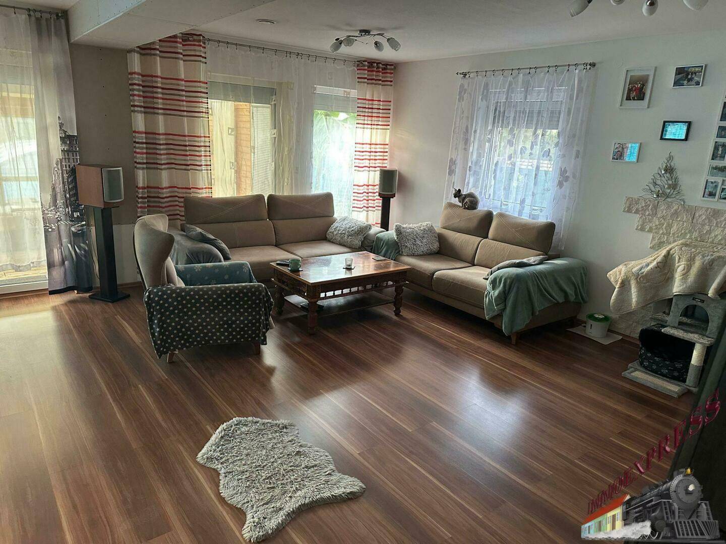 Geräumiges Wohnzimmer mit Holzboden, bequemen Sofas und einem großen Fernseher.