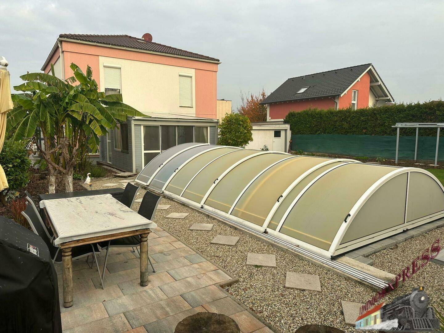 Gartenbereich mit großem Esstisch im Freien und der Abdeckung des Swimmingpools.