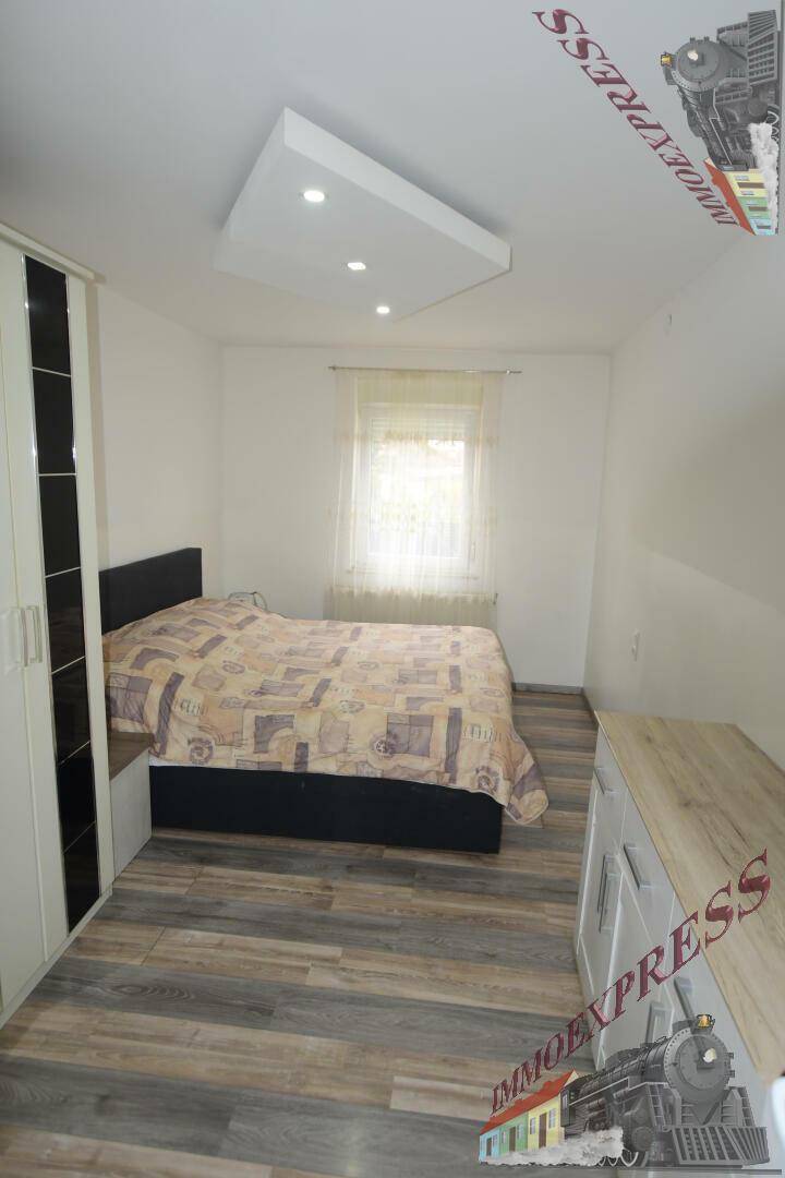 Helles Schlafzimmer mit Doppelbett, Kleiderschrank und Laminatboden.