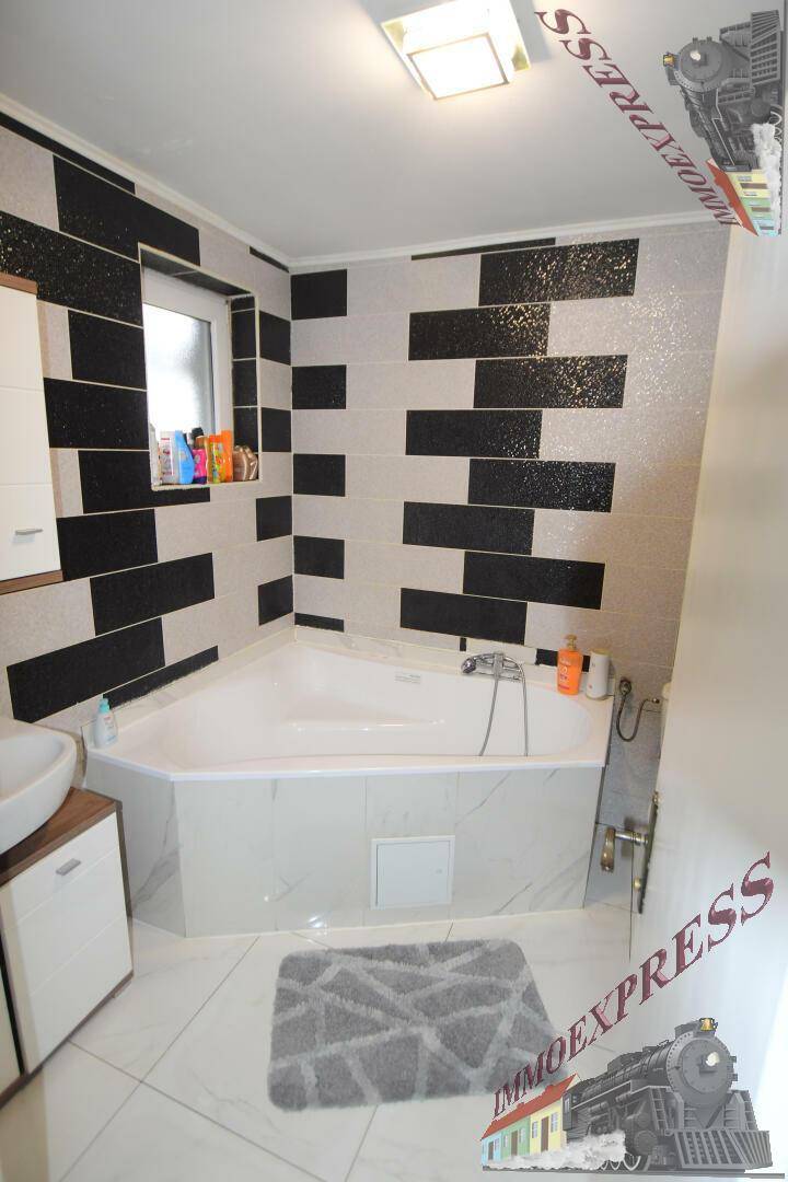 Modernes Badezimmer mit Eckbadewanne, schwarz-weißen Fliesen und Waschbecken.
