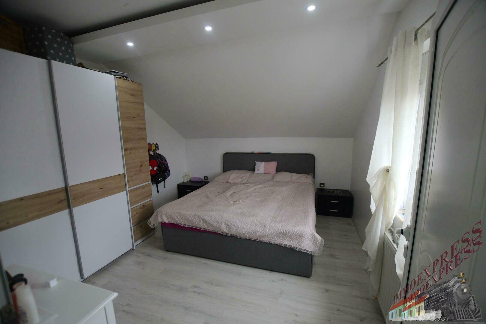 Geräumiges Schlafzimmer im Dachgeschoss mit Doppelbett, Kleiderschrank und Laminatboden.