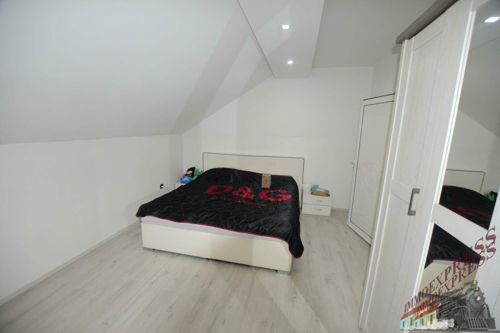 Helles Schlafzimmer im Dachgeschoss mit Doppelbett, Kleiderschrank und Laminatboden.