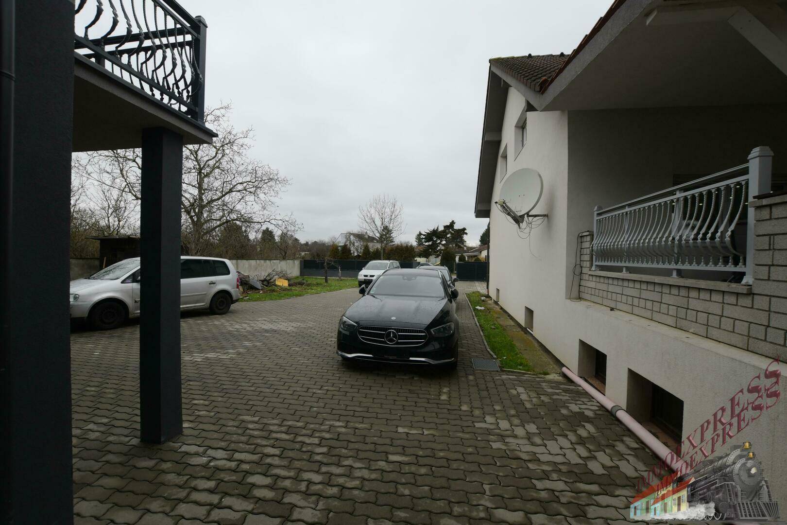 Gepflasterte Einfahrt mit parkenden Autos und Blick auf die Hausfassade.
