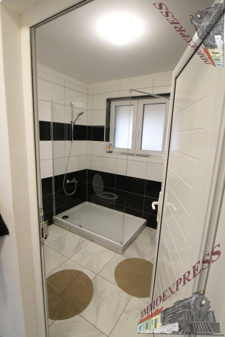 Modernes Badezimmer mit Duschkabine, schwarz-weißen Fliesen und Fenster.