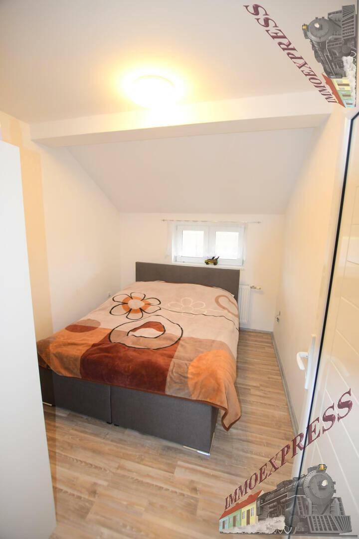 Gemütliches Schlafzimmer im Dachgeschoss mit Doppelbett, Laminatboden und Dachschräge.