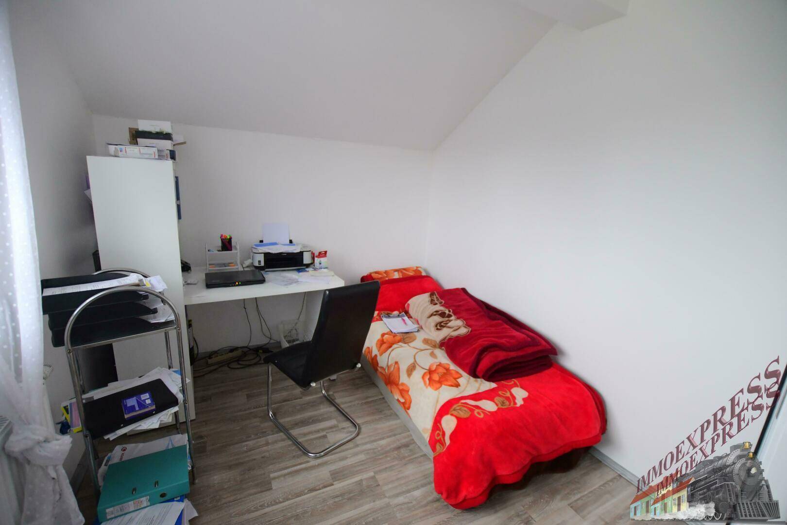 Kleines Schlafzimmer im Dachgeschoss mit Einzelbett, Schreibtisch und Laminatboden.