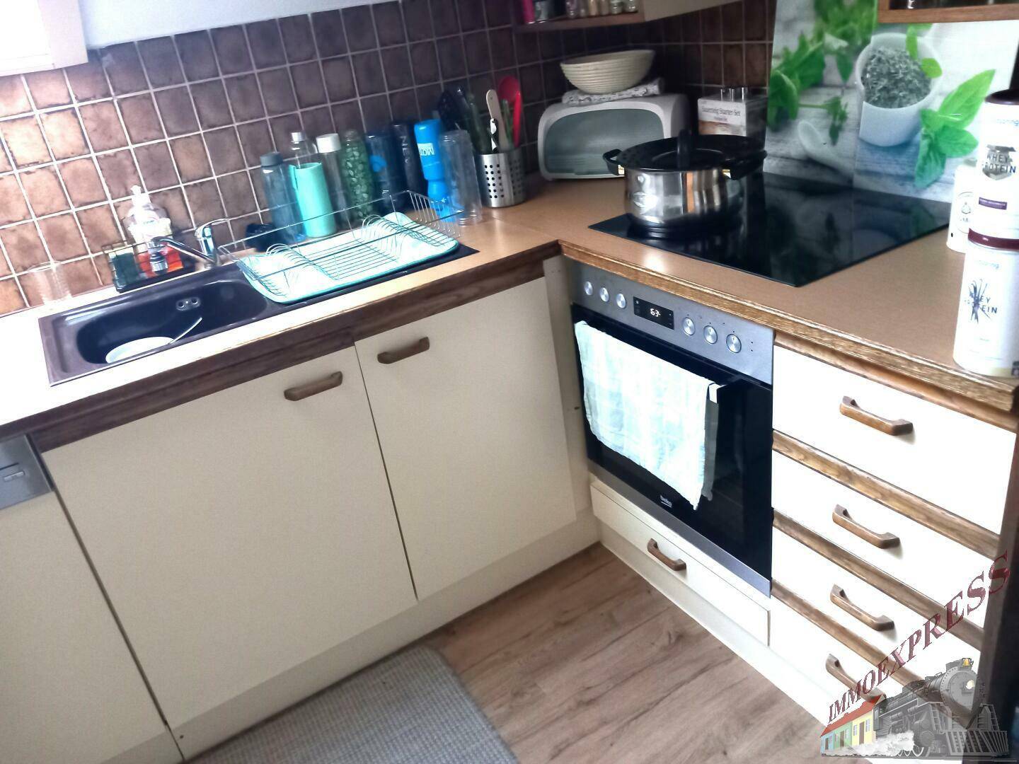 Funktionale Küche mit Einbaugeräten, braunen Fliesen und Holz-Arbeitsplatten.