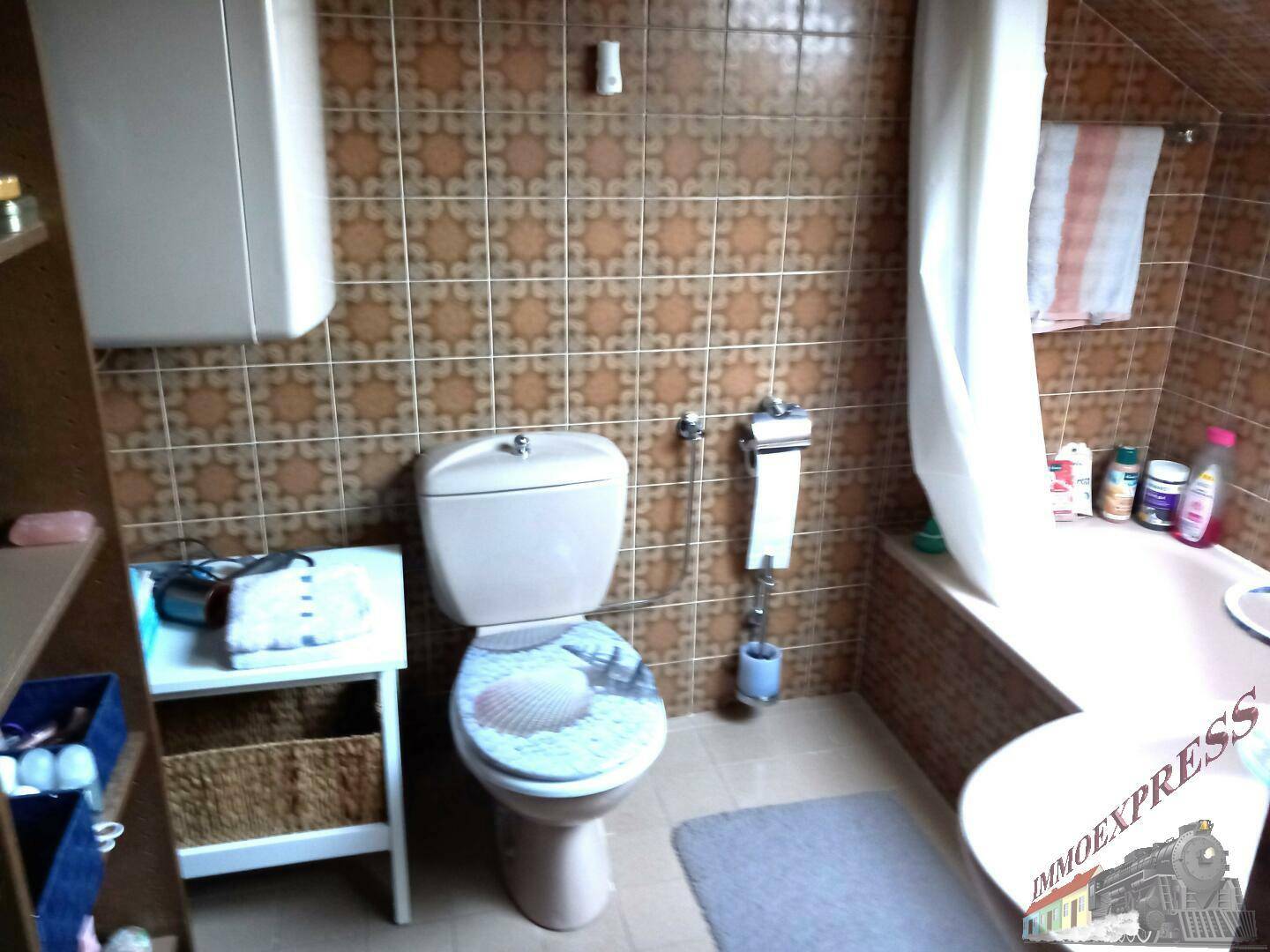 Badezimmer mit Toilette, Badewanne und braunen Fliesen im Retro-Stil.