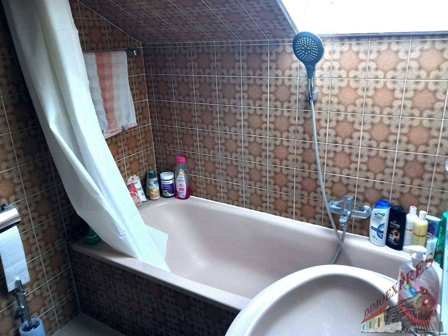 Badezimmer mit Badewanne und braunen Retro-Fliesen an Wänden und Boden.
