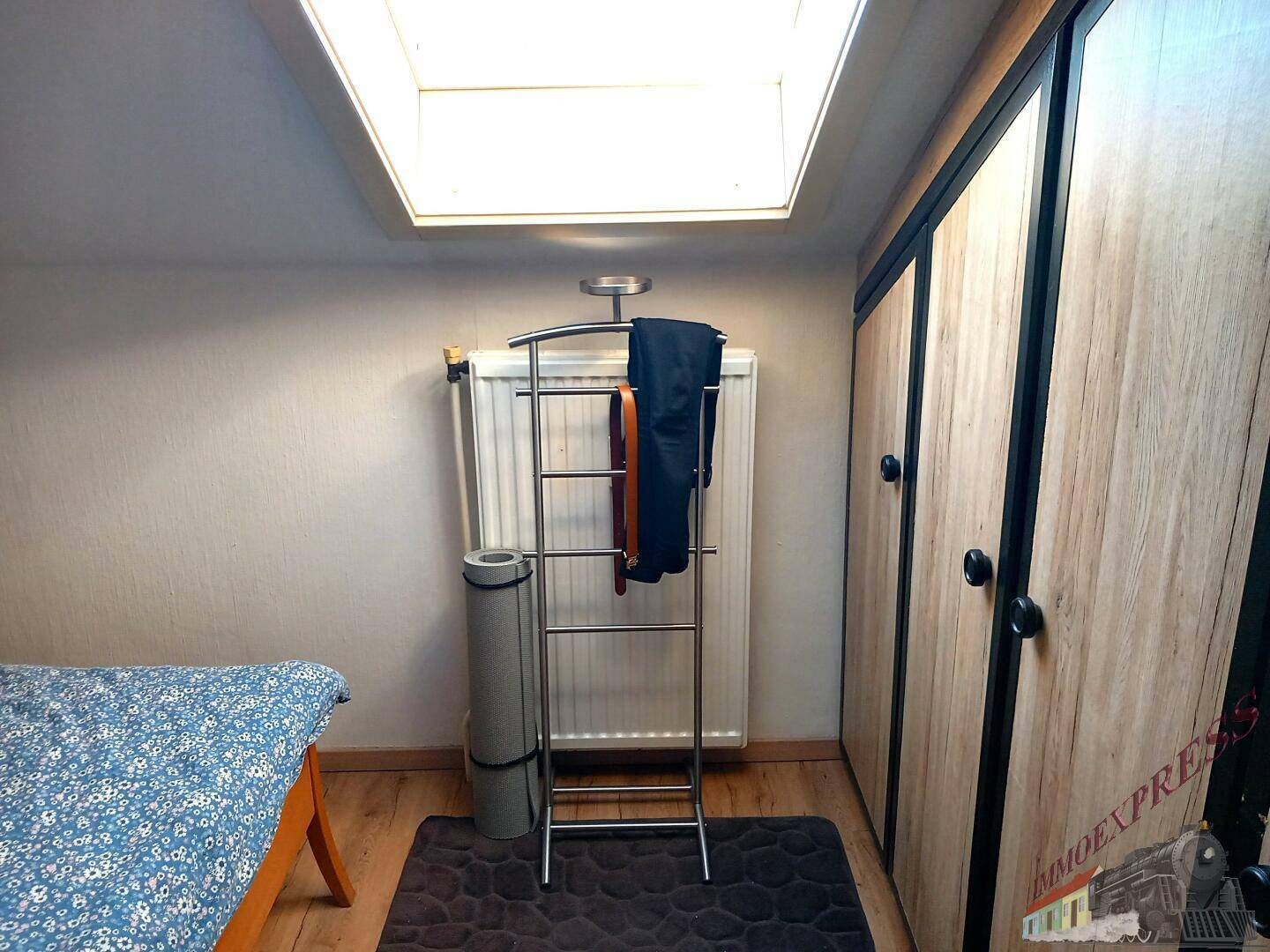 Schlafzimmer mit Dachfenster, Kleiderschrank und Heizkörper.