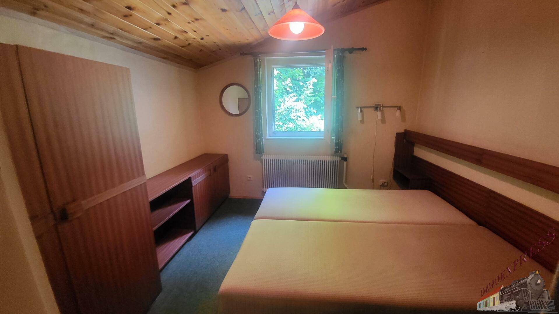 Gemütliches Schlafzimmer mit zwei Einzelbetten, Holzdecke und Blick ins Grüne.