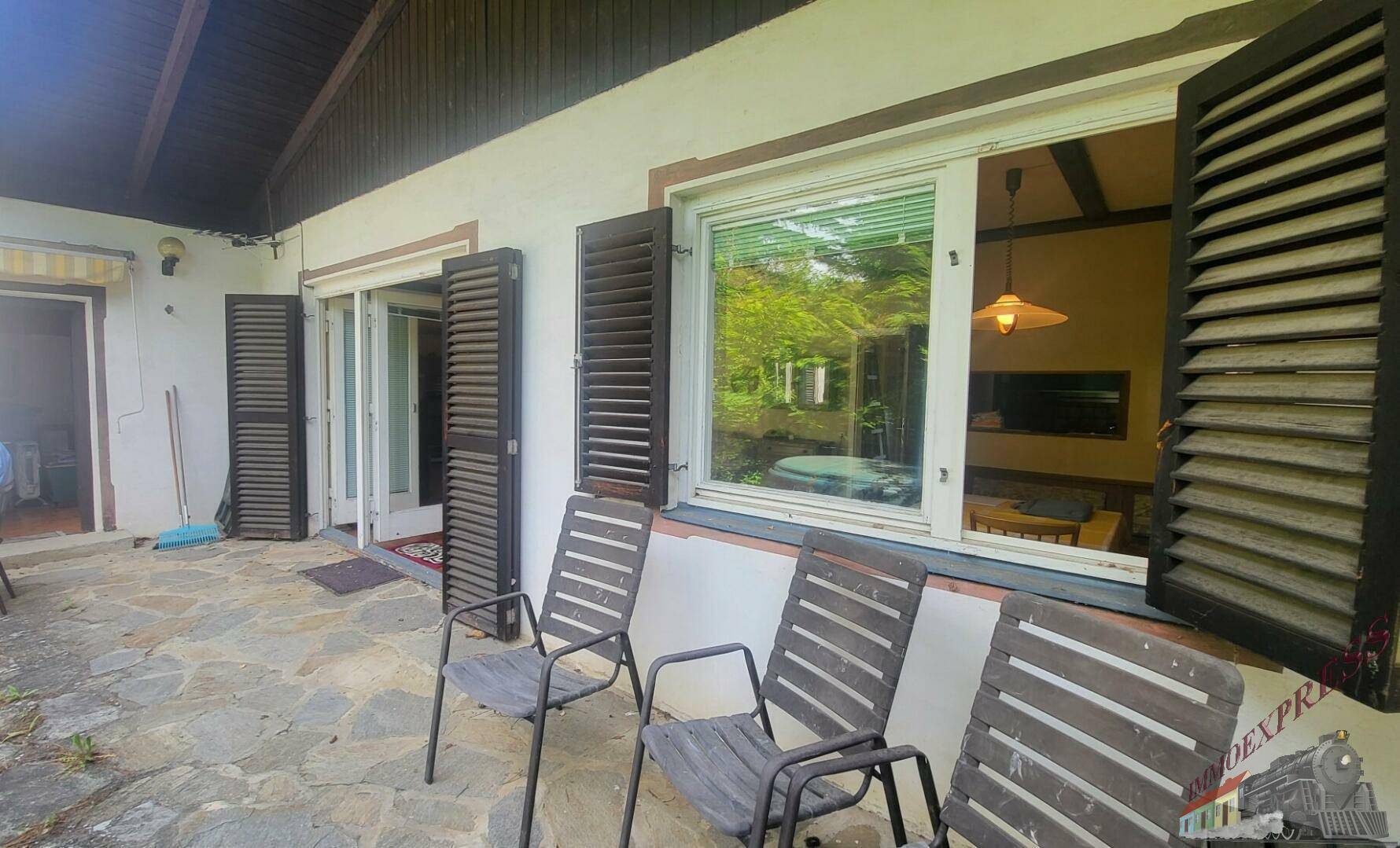 Gepflasterte Terrasse mit Gartenstühlen und Blick ins Grüne, direkt am Haus gelegen.