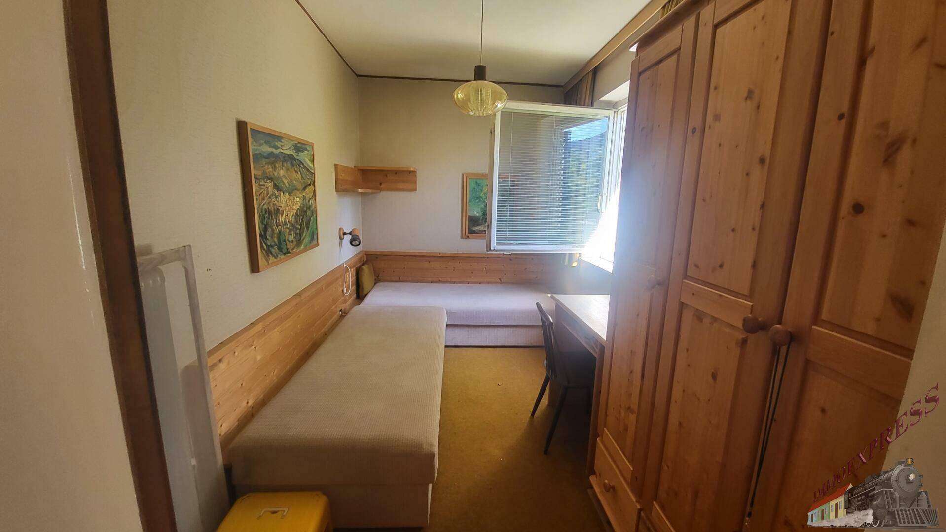 Helles Schlafzimmer mit Holzmöbeln, Einzelbetten und Blick ins Grüne.