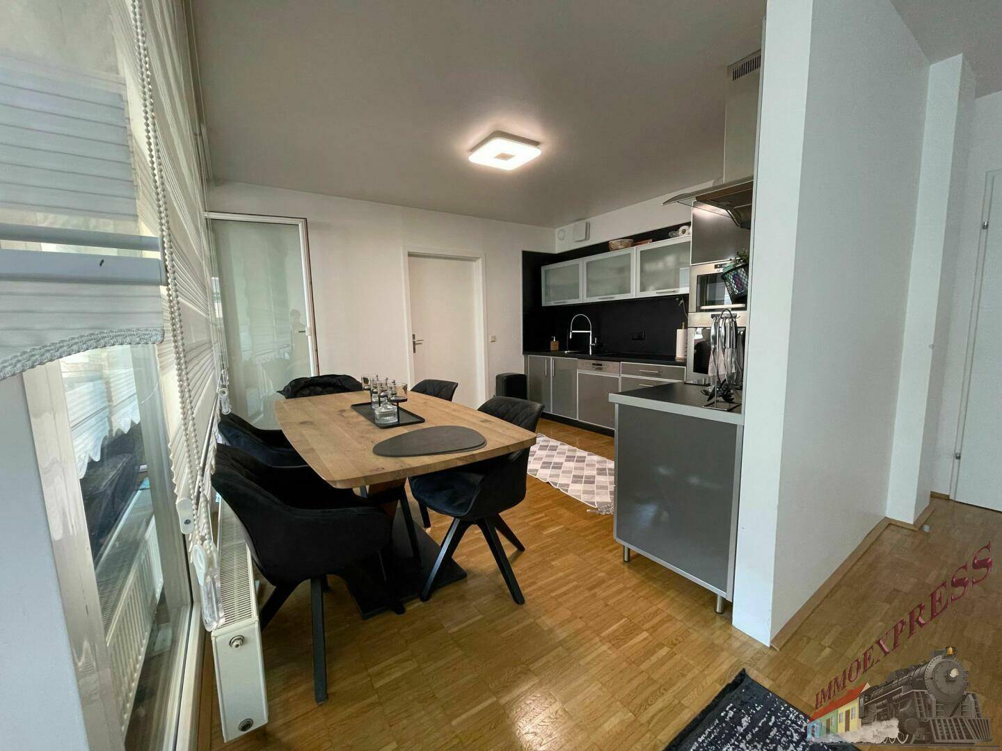 Offener Essbereich mit Holztisch und Zugang zur modernen Küche, ideal für gesellige Abende.