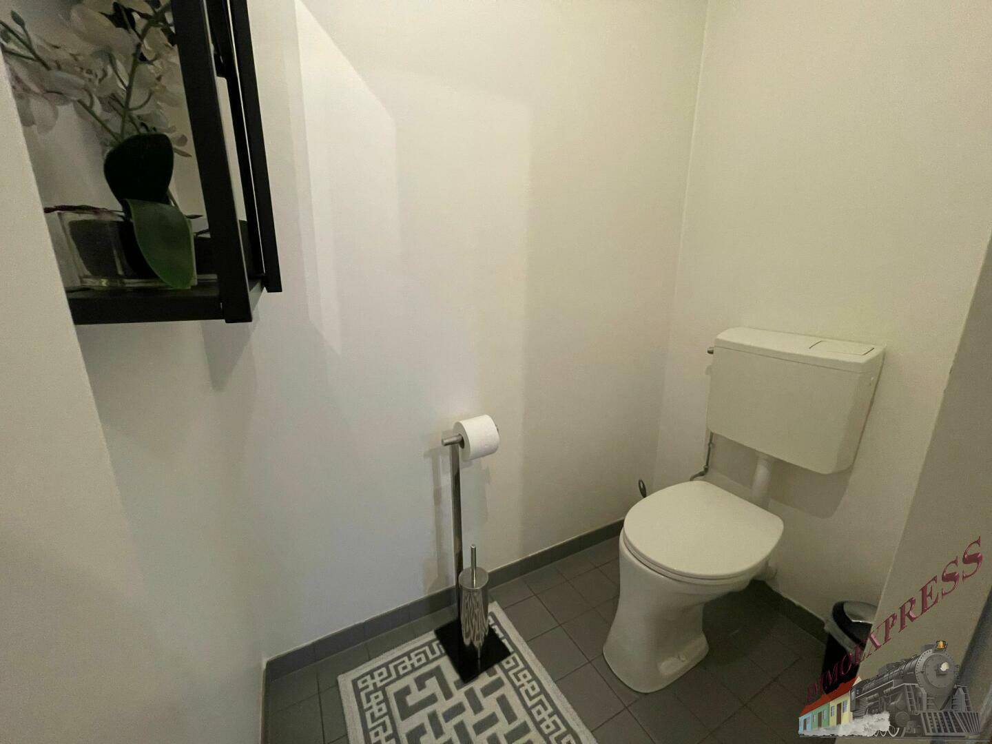 Kleines Gäste-WC mit Toilette und dunklem Fliesenboden, funktional und sauber.