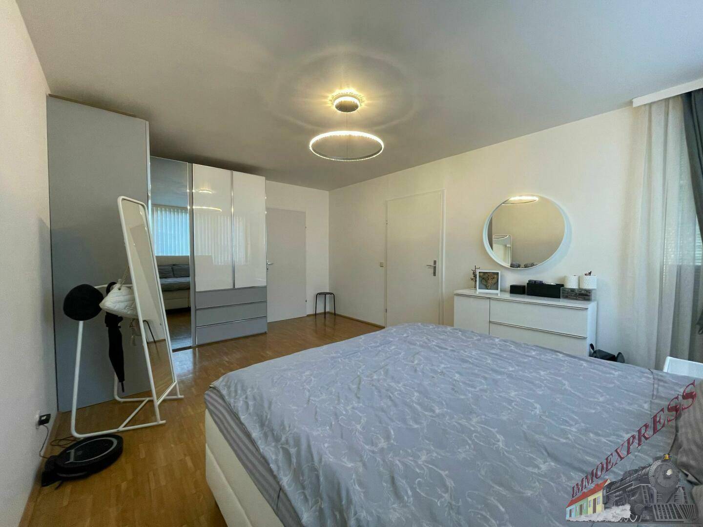 Geräumiges Schlafzimmer mit Holzboden, großem Kleiderschrank und modernem Spiegel.