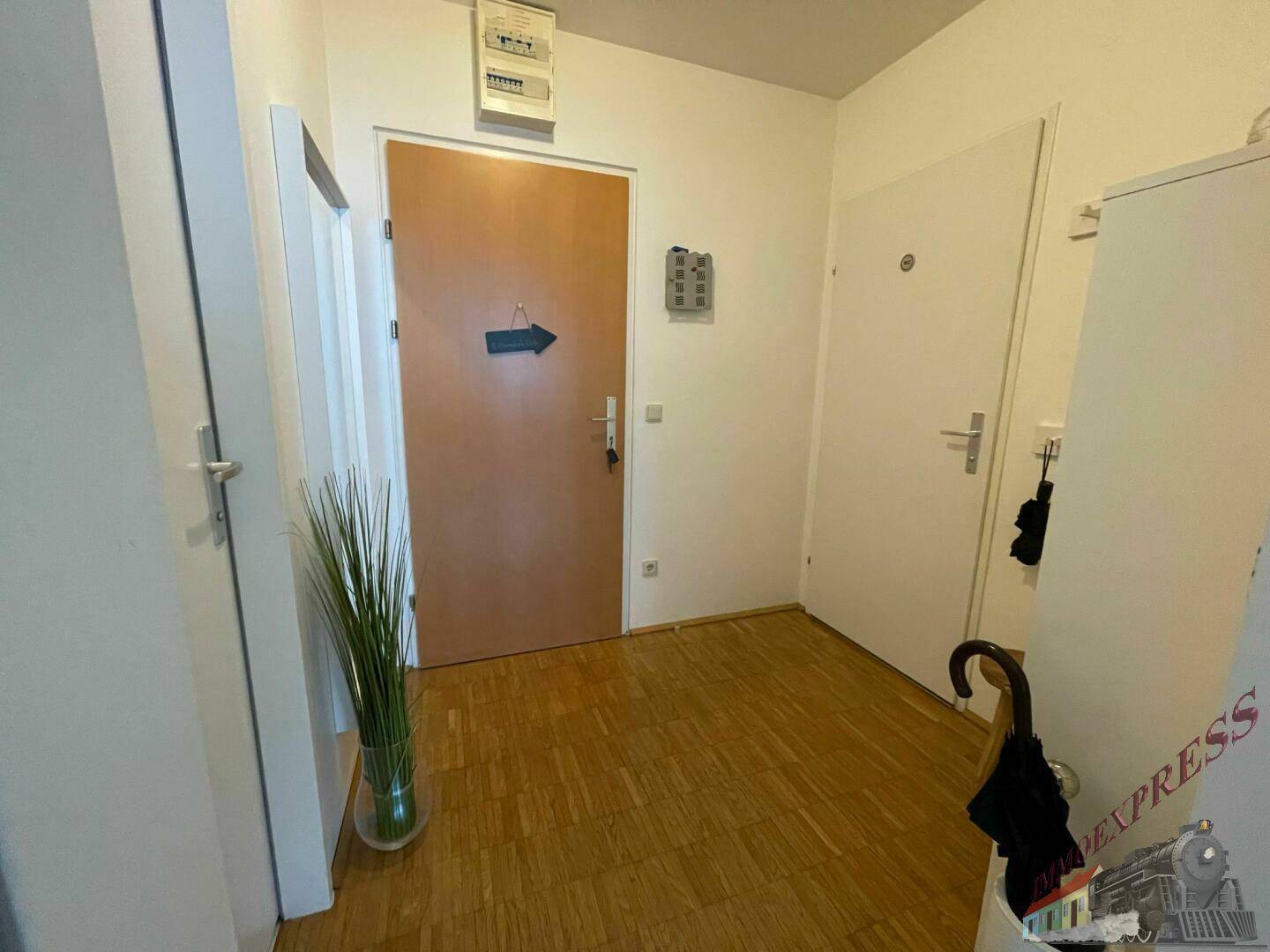 Heller Eingangsbereich mit Holzboden und zwei Türen, die zu weiteren Räumen führen.