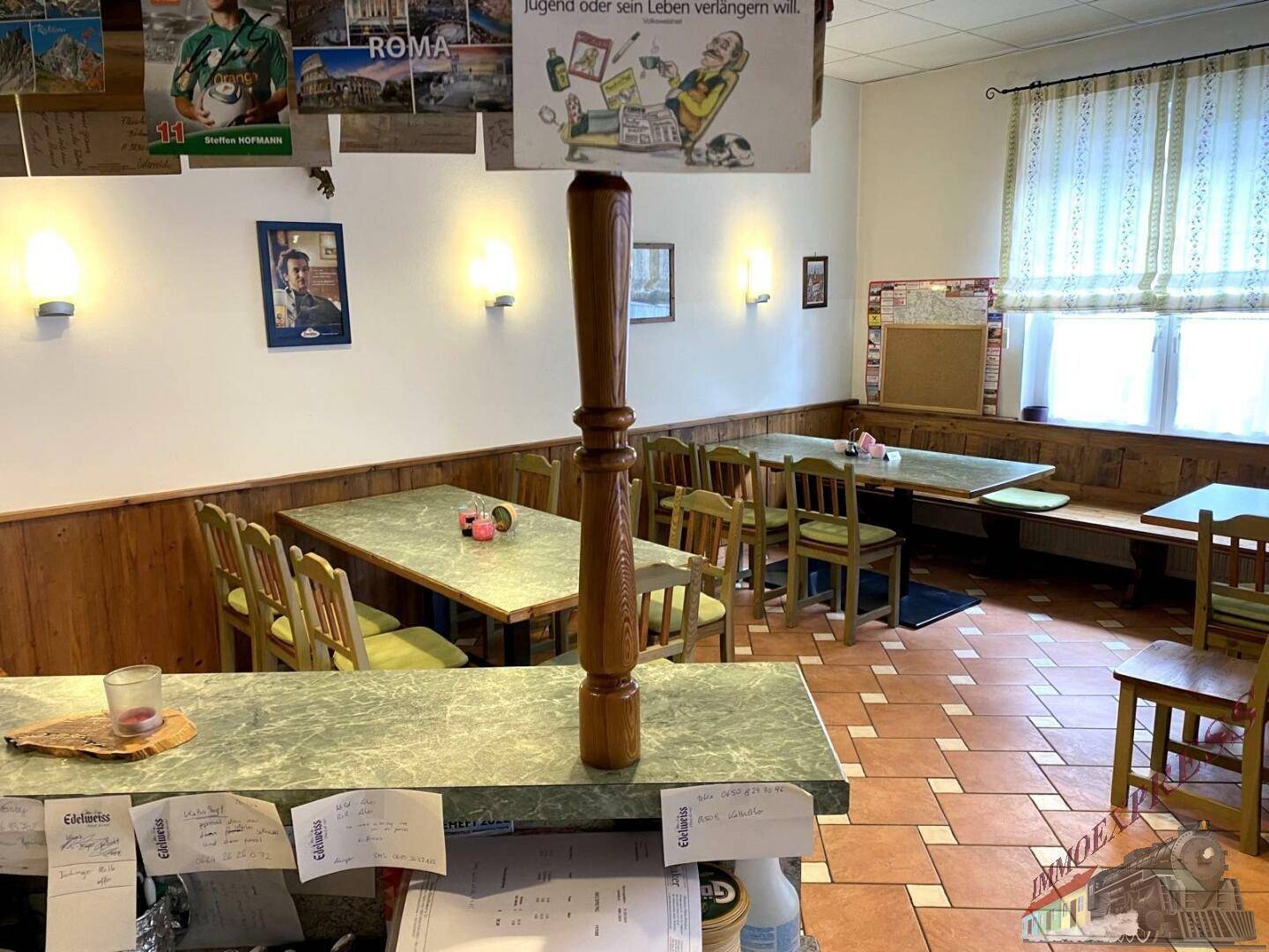 Gemütlicher Essbereich mit Holztischen und Stühlen, Fliesenboden und Wandverkleidung aus Holz.