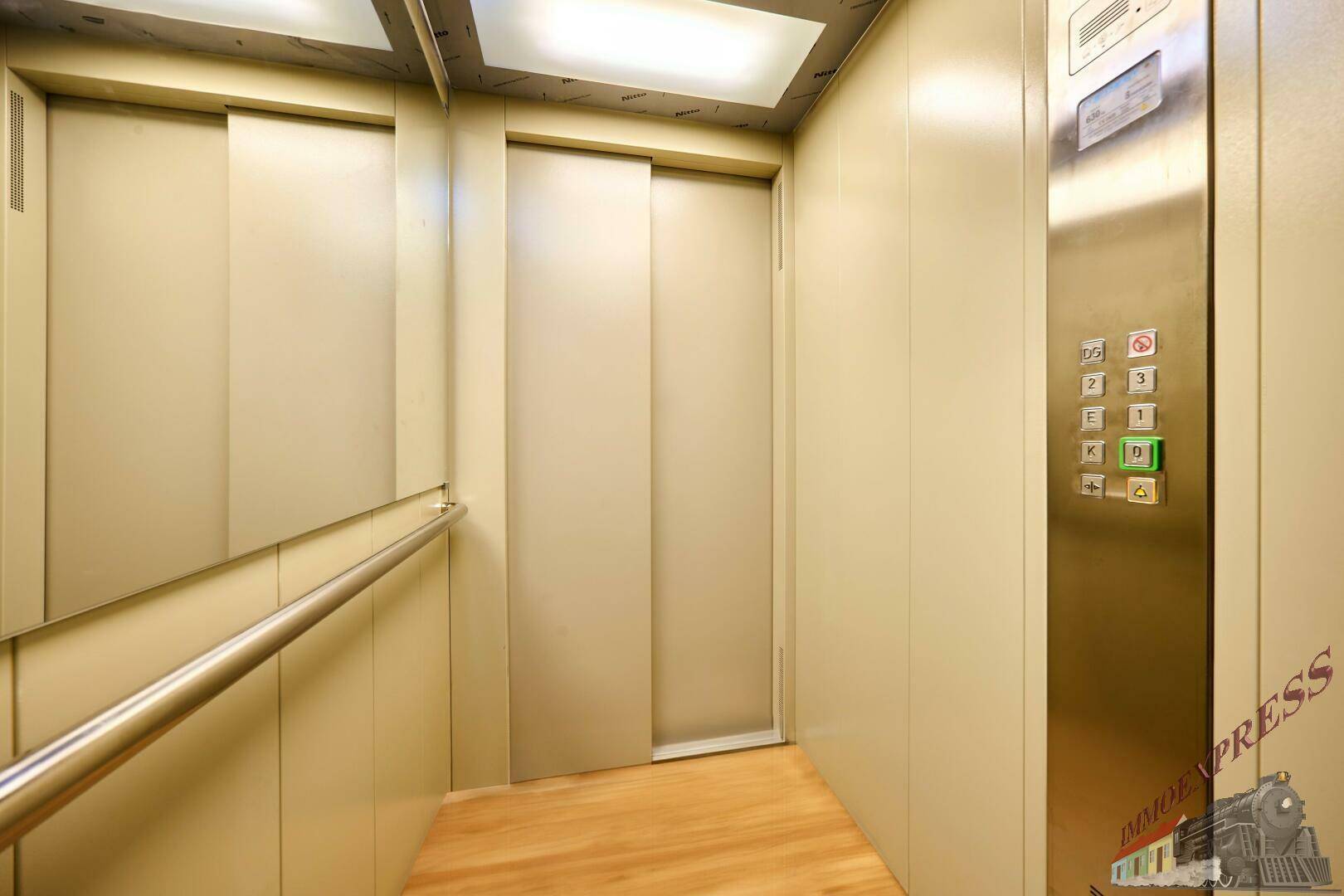Innenansicht eines modernen Aufzugs mit Holzfußboden und Handlauf.