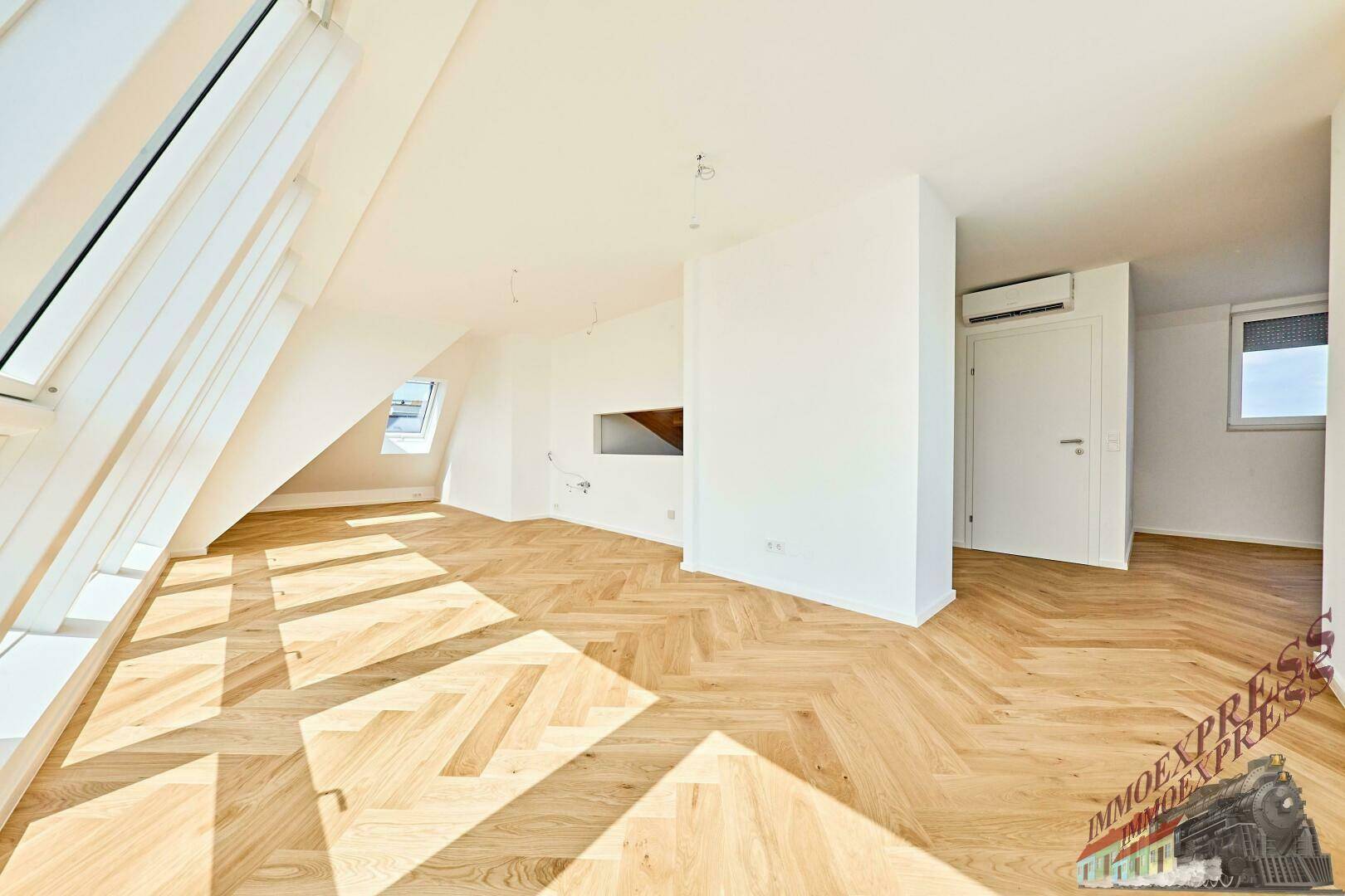 Geräumiger Wohnraum mit Fischgrätparkett, Klimaanlage und schrägen Dachfenstern.