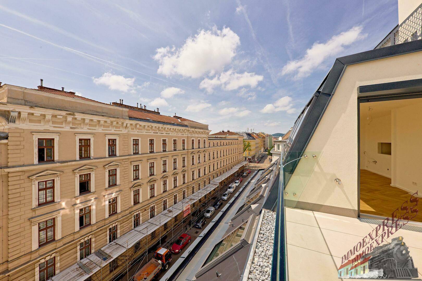 Blick von einem Balkon auf die gegenüberliegende historische Fassade und die Straße.