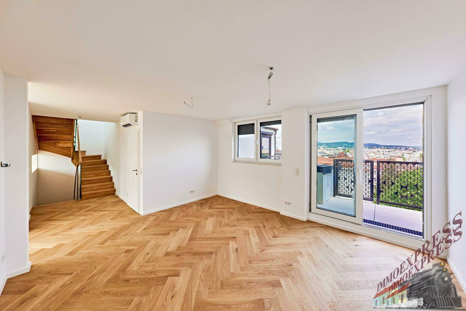 Heller Wohnraum mit Fischgrätparkett, Klimaanlage und Zugang zu einem Balkon.