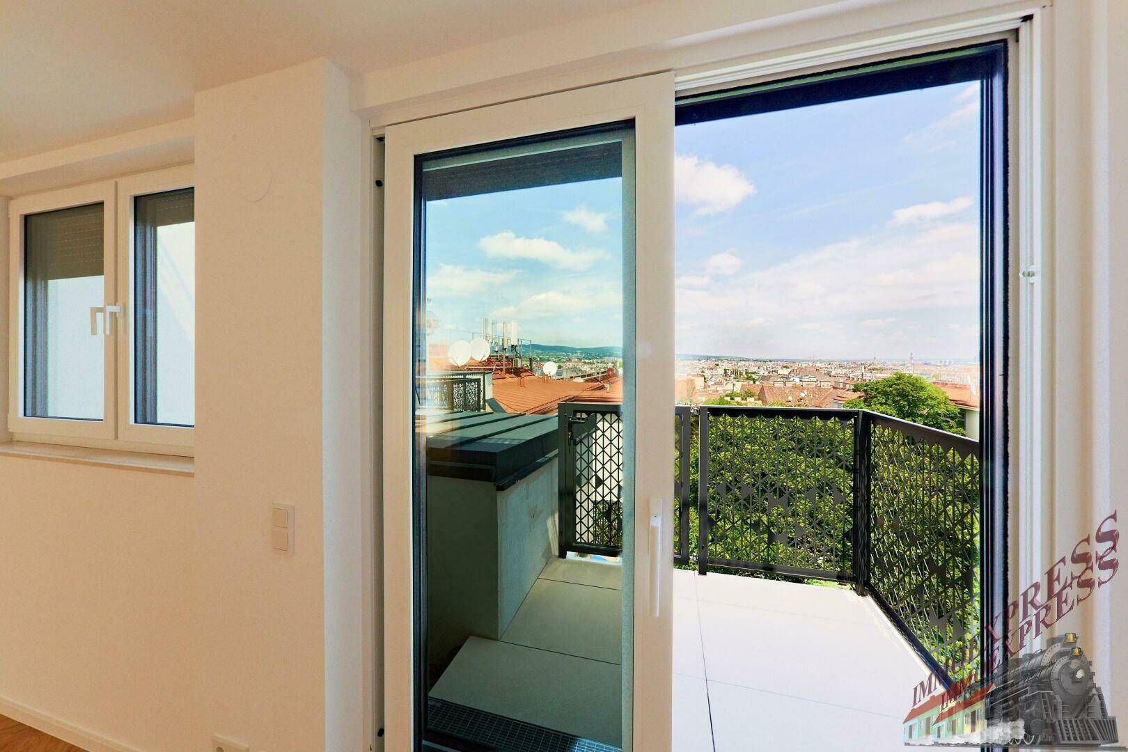 Heller Raum mit Zugang zu einem Balkon und weitem Blick auf die Stadt.