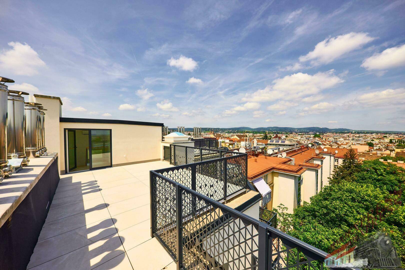 Geräumige Dachterrasse mit Fliesenboden und Blick auf die Stadt und umliegende Gebäude.