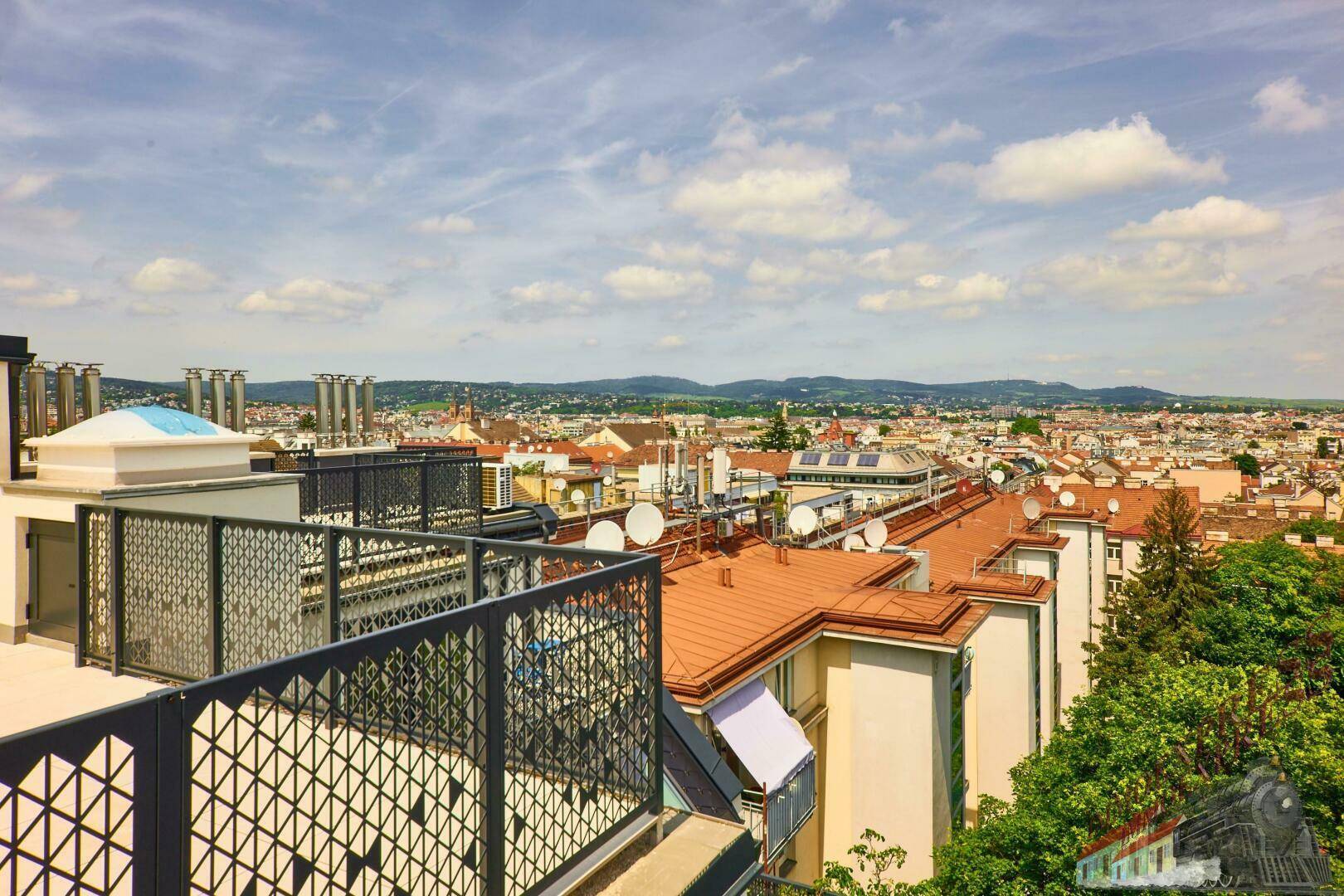 Dachterrasse mit moderner Brüstung und weitem Blick über die Stadt und grüne Umgebung.
