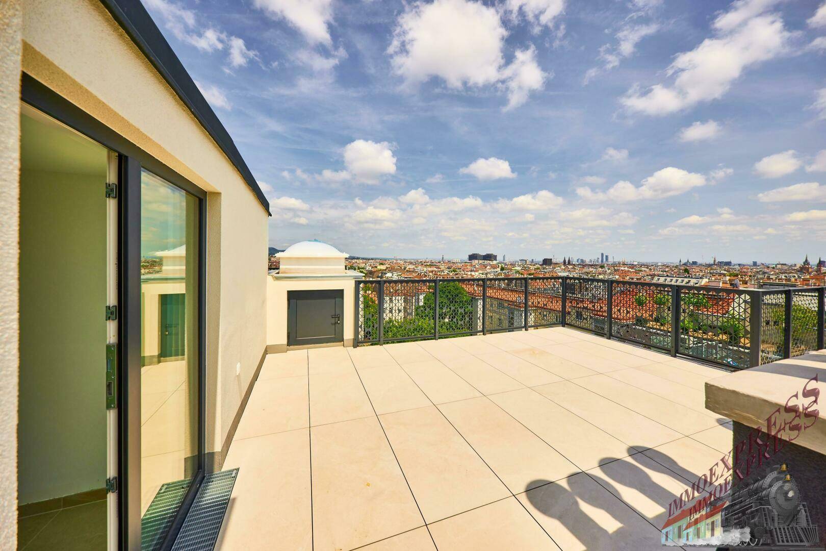 Weitläufige Dachterrasse mit Fliesenboden und Panoramablick über die Stadtlandschaft.