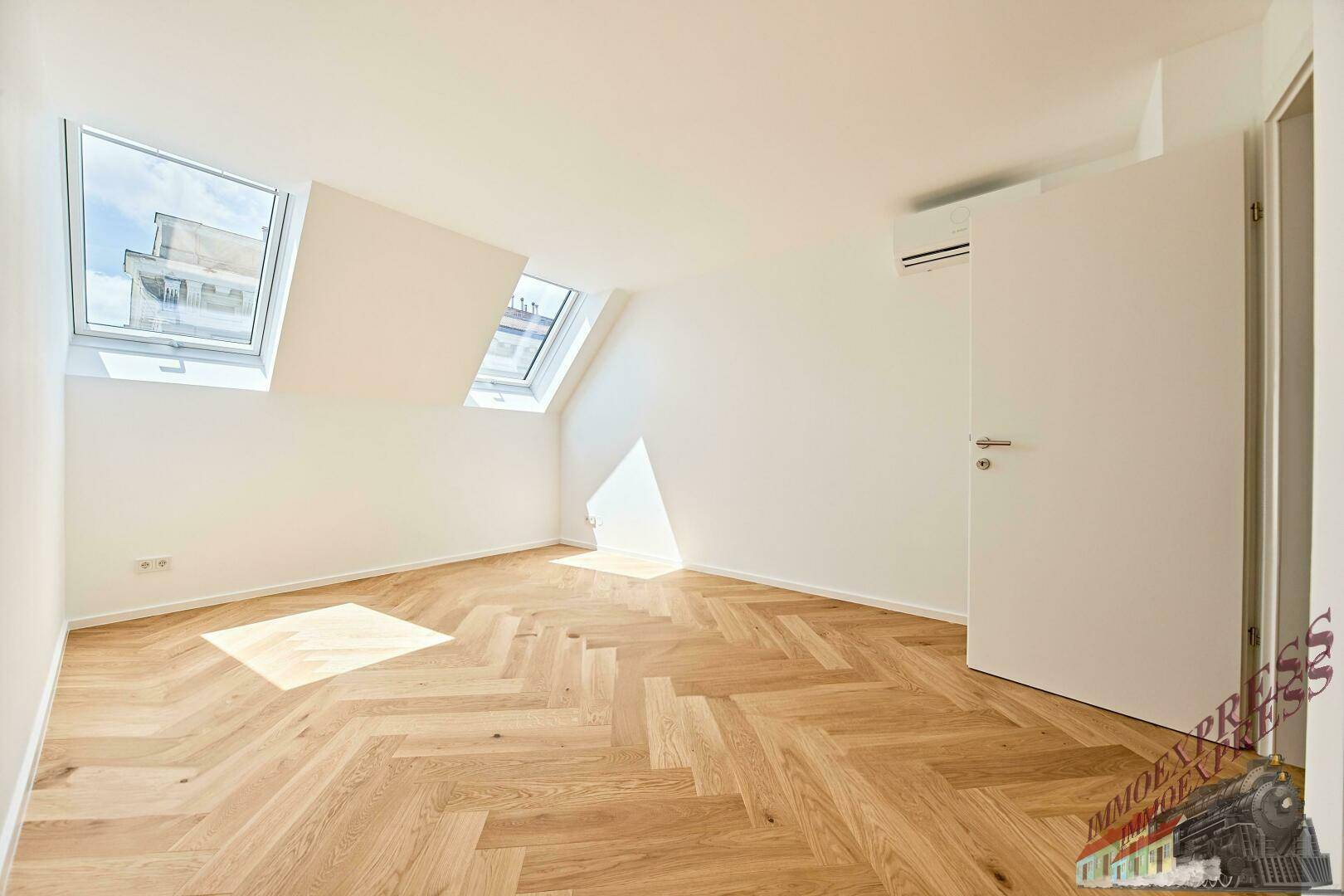 Helles Schlafzimmer mit Fischgrätparkett, Klimaanlage und zwei Dachfenstern.