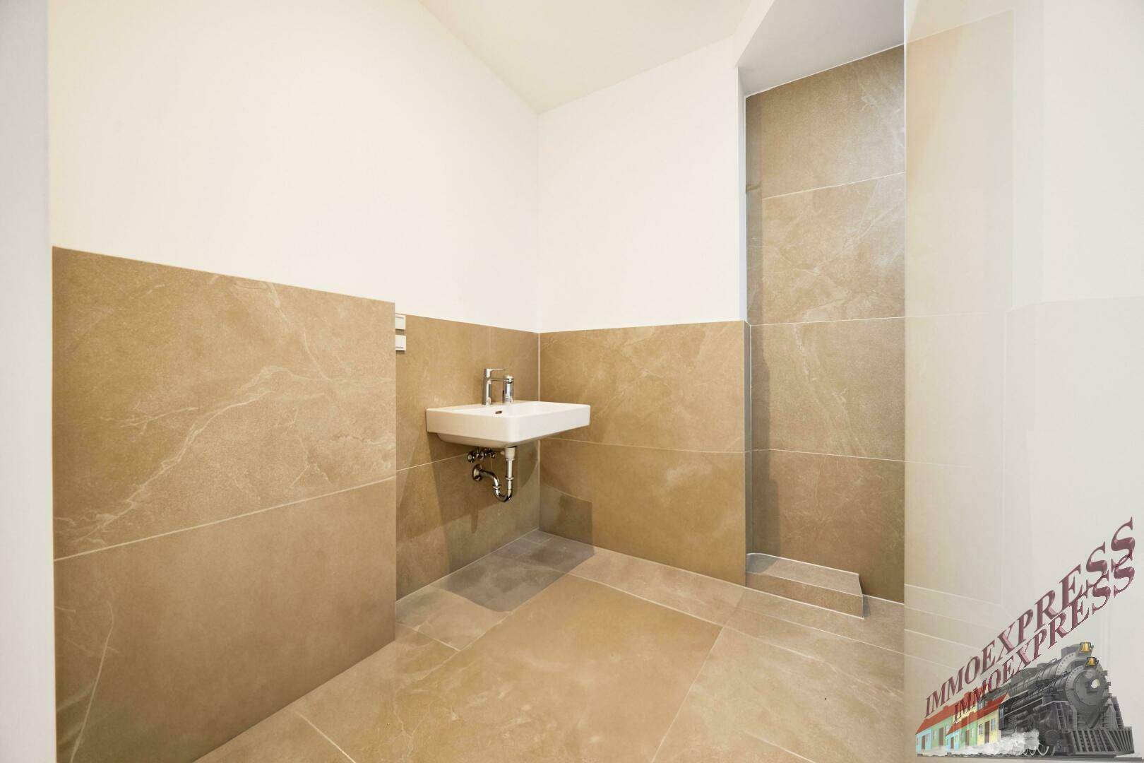 Modernes WC mit beigefarbenen Fliesen und einem kleinen, stilvollen Waschbecken.