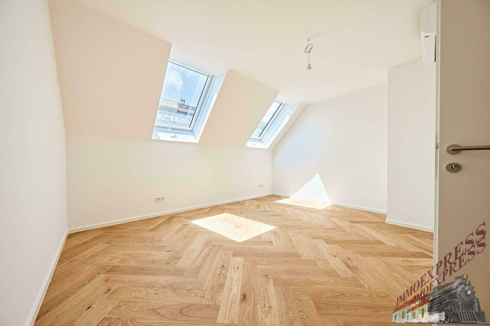 Helles Schlafzimmer mit Fischgrätparkett und zwei Dachfenstern, bietet viel Tageslicht.