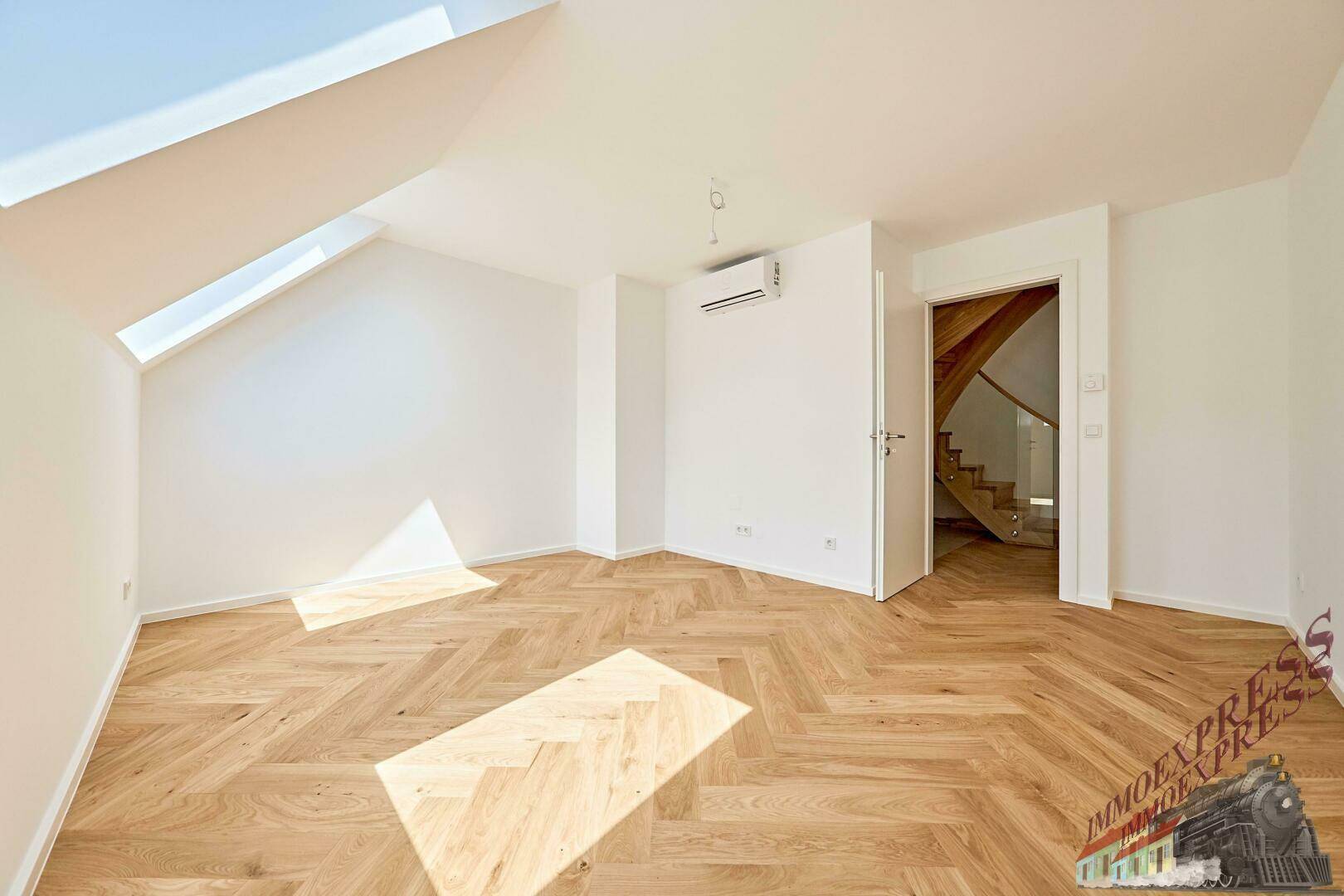 Helles Schlafzimmer mit Fischgrätparkett, Klimaanlage und Zugang zu einer Tür.
